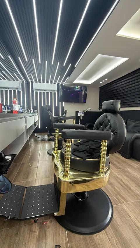 Silla de barbero en cuero negro con base dorada